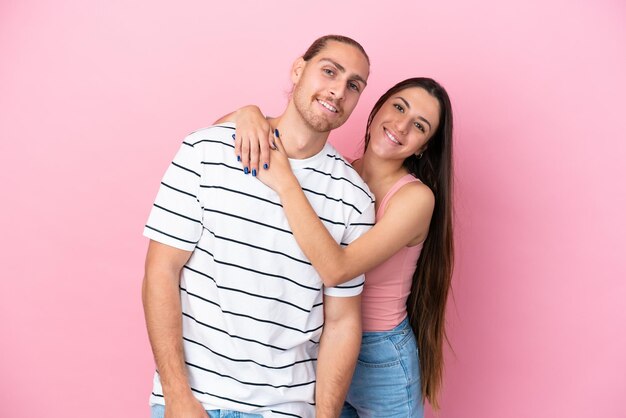 Joven pareja caucásica aislada sobre fondo rosa abrazándose