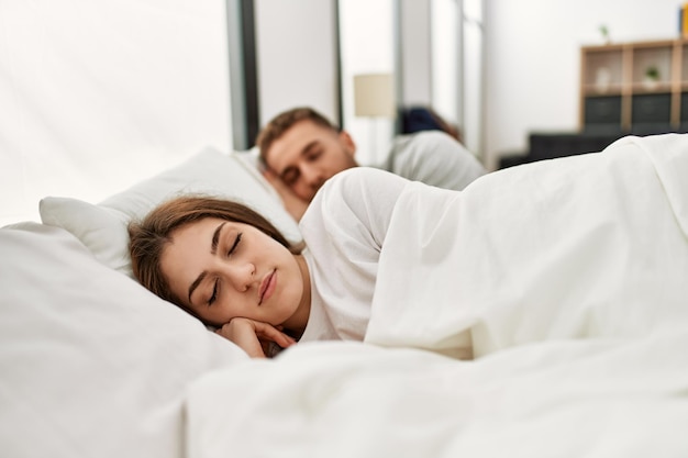 Joven pareja caucásica durmiendo en la cama en casa.