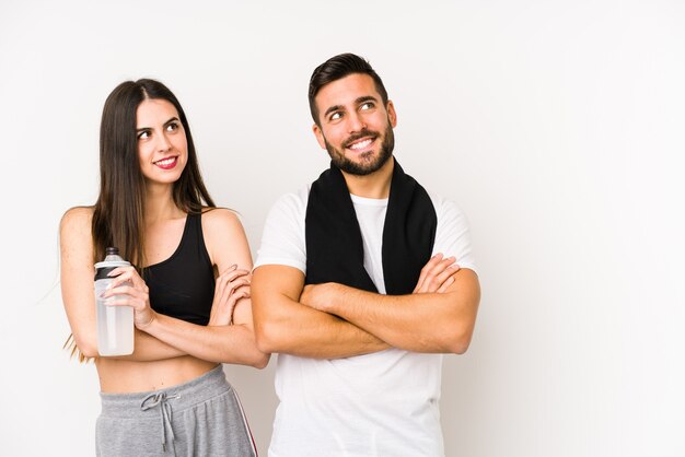 Joven pareja caucásica fitness aislado sonriendo confiado con los brazos cruzados.