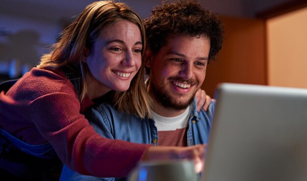 Una joven pareja caucásica usando una computadora portátil juntos en casa buscando un destino de viaje