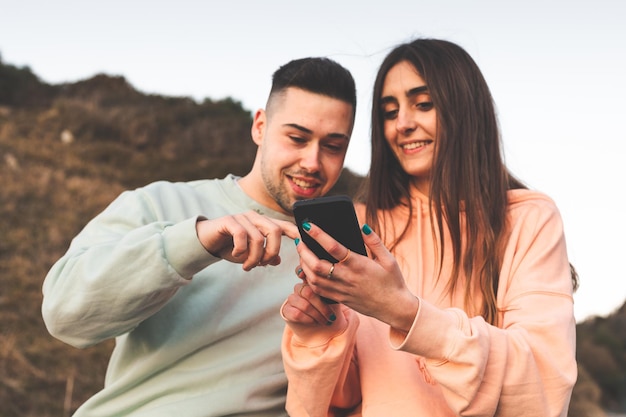 Joven pareja caucásica usando un teléfono inteligente en la naturaleza