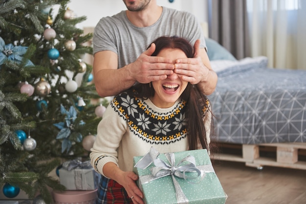 Joven pareja celebrando la Navidad. Un hombre de repente presentó un regalo a su esposa. El concepto de felicidad y bienestar familiar.