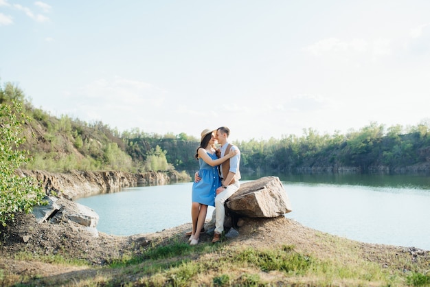 Una joven pareja, un chico y una chica están caminando cerca de un lago de montaña rodeado de rocas de granito