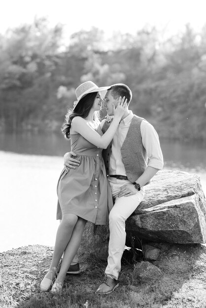 Una joven pareja, un chico y una chica están caminando cerca de un lago de montaña rodeado de rocas de granito