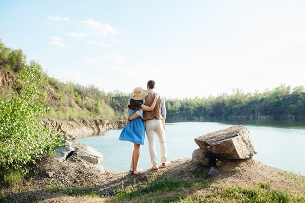 Una joven pareja, un chico y una chica están caminando cerca de un lago de montaña rodeado de rocas de granito