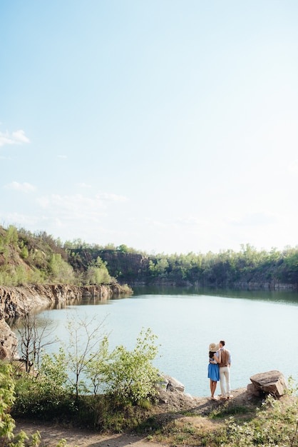 Una joven pareja, un chico y una chica están caminando cerca de un lago de montaña rodeado de rocas de granito