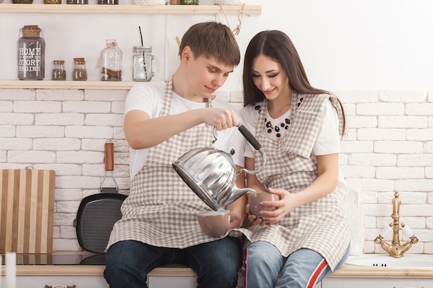 Joven pareja en la cocina. Hombre y mujer cocinando. Novio y novia en el interior en la cocina.