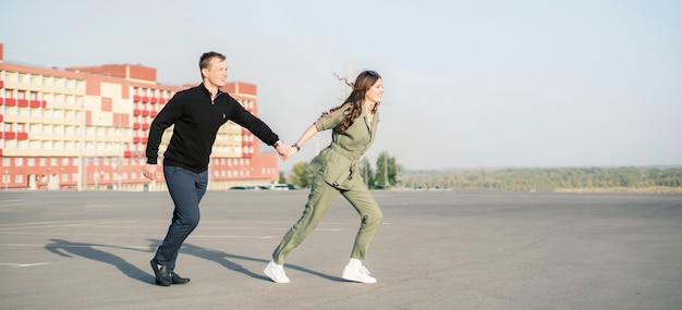 Una joven pareja corre en la calle el día de verano cogidos de la mano, vacaciones de fin de semana feliz vida