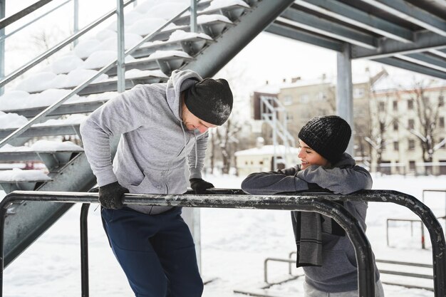 Joven pareja deportiva durante el entrenamiento de calistenia durante el frío invierno y el día de nieve