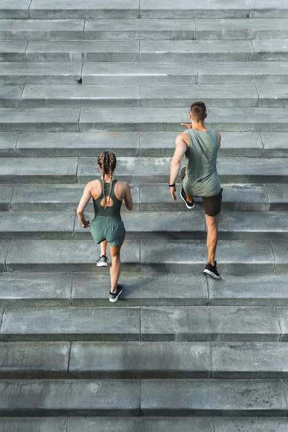 Joven pareja deportiva durante la escalera de entrenamiento corriendo al aire libre