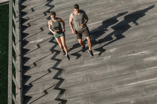 Joven pareja deportiva durante la escalera de entrenamiento corriendo al aire libre