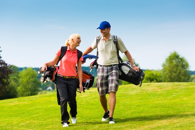 Joven pareja deportiva jugando al golf en un curso