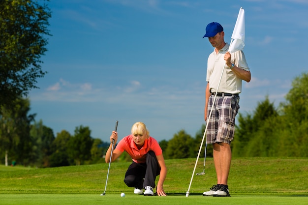 Joven pareja deportiva jugando al golf en un curso