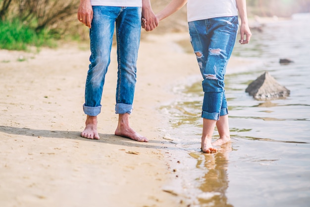 Joven pareja descalza caminando por la playa. pies en el agua verano