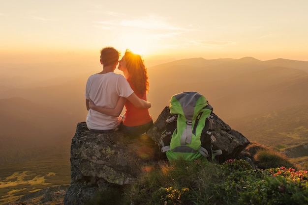 Joven pareja disfruta juntos hermosa puesta de sol en las montañas