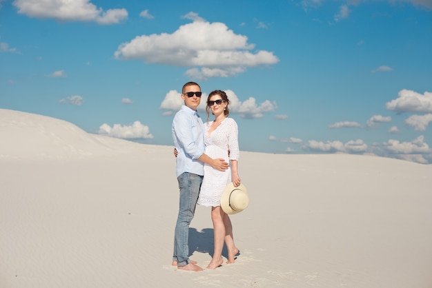 Joven pareja disfrutando del atardecer en las dunas. Viajero romántico camina en el desierto. Concepto de estilo de vida de viajes de aventura
