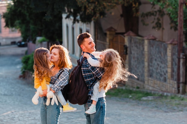 La joven pareja con dos hijas recorre las calles del casco antiguo Papá y mamá sostienen a sus hijos en brazos