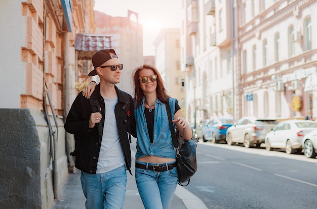 Joven pareja elegante camina por la ciudad con gafas de sol. Camina vistas cita chico chica.