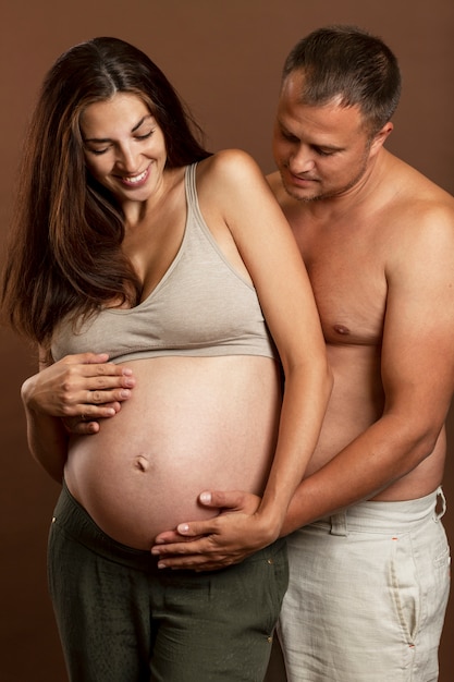 Joven pareja embarazada abrazando y sonriendo. Amor y ternura. La felicidad está esperando una nueva vida. Vertical.