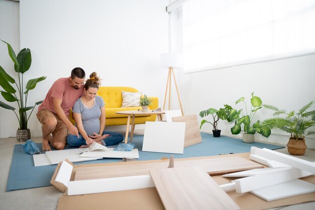 Una joven pareja embarazada montando muebles arreglando la casa para la llegada de un nuevo bebé