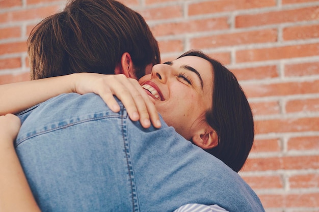 La joven pareja enamorada se abraza en el fondo de una pared de ladrillo rojo Una pareja feliz en relación disfruta de actividades de ocio en el interior juntos abrazándose Momentos románticos hombre y mujer