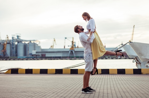 Foto una joven pareja enamorada divirtiéndose en el puerto. el hombre apoya a la mujer.