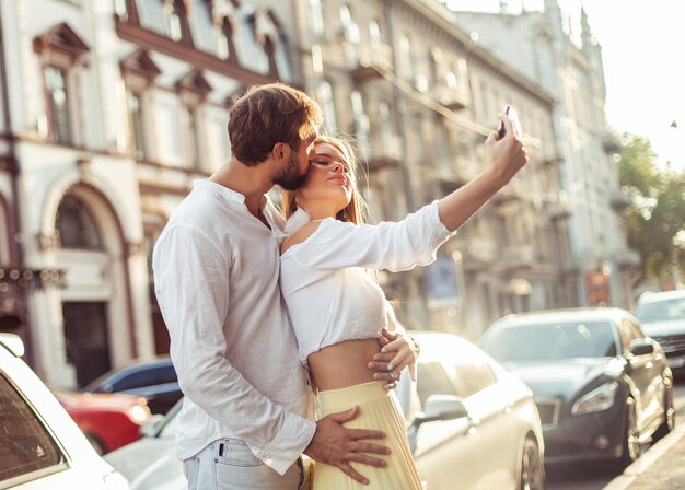 Foto una joven pareja enamorada se hace una selfie en un teléfono inteligente en la ciudad concepto de amor romántico