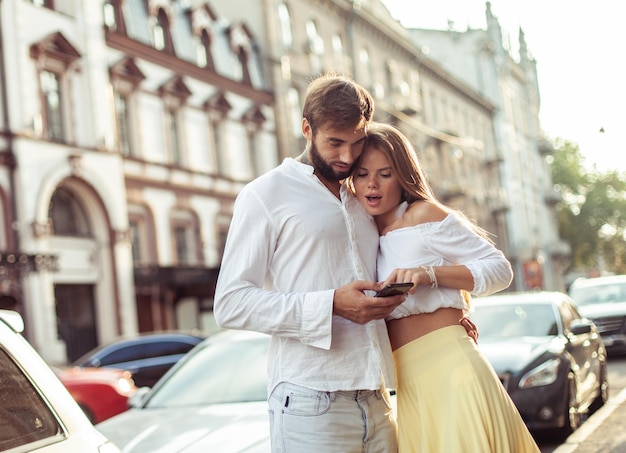 Una joven pareja enamorada mirando la pantalla de un teléfono inteligente en la ciudad