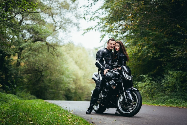Foto joven pareja enamorada en una motocicleta en la carretera en el bosque