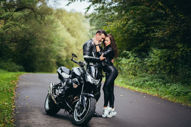 joven pareja enamorada en una motocicleta en la carretera en el bosque