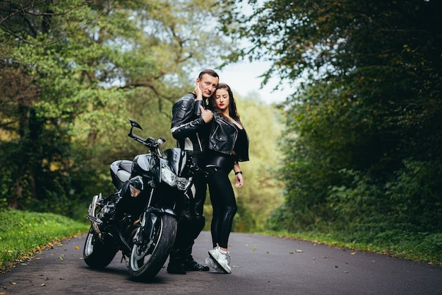 joven pareja enamorada en una motocicleta en la carretera en el bosque