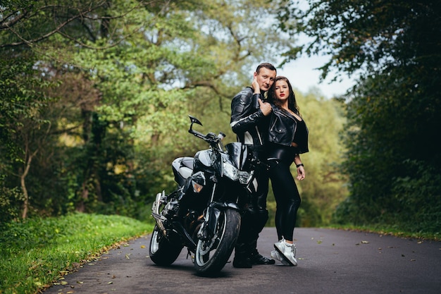 joven pareja enamorada en una motocicleta en la carretera en el bosque