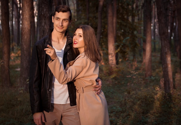 Joven pareja de enamorados abrazándose en el bosque de otoño