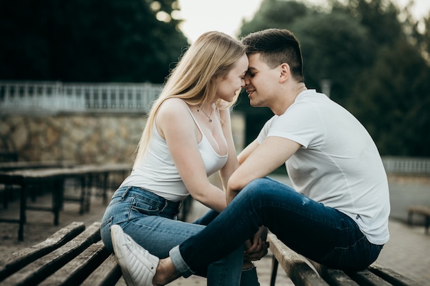 Una joven pareja de enamorados besándose en el banco en el parque