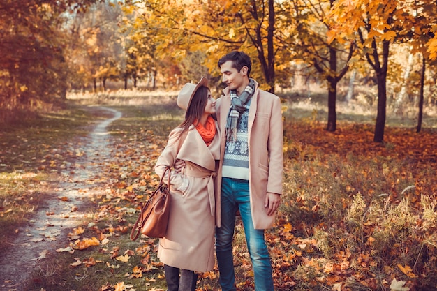 Joven pareja de enamorados camina en el bosque de otoño entre árboles coloridos