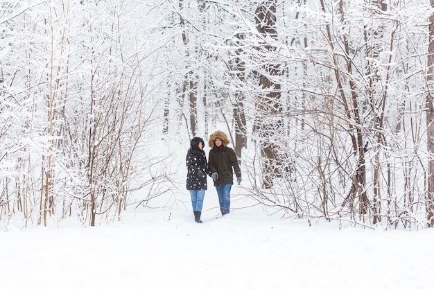 Joven pareja de enamorados camina en las vacaciones de invierno activas del bosque nevado