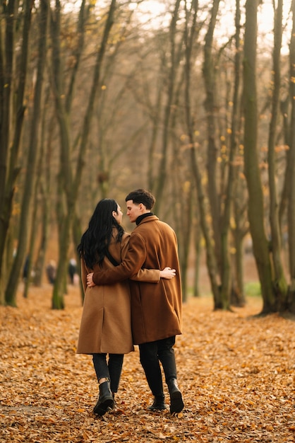 Joven pareja de enamorados caminando en el parque en un día de otoño