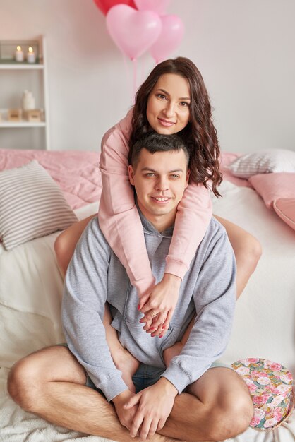 Joven pareja de enamorados en casa en la cama celebrando el Día de San Valentín