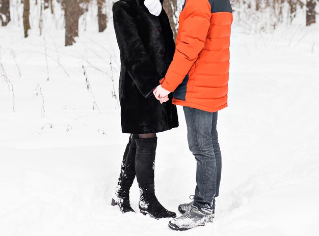 Joven pareja de enamorados cogidos de la mano al aire libre en invierno.