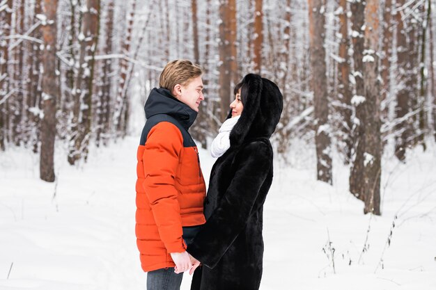 Joven pareja de enamorados cogidos de la mano al aire libre en la naturaleza de invierno.