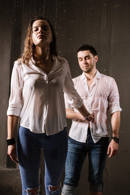 Joven pareja de enamorados compartiendo momentos románticos bajo la lluvia. Besarse y divertirse bajo la lluvia.