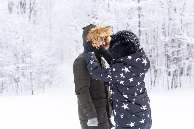 Joven pareja de enamorados se divierten en el bosque nevado. Vacaciones de invierno activas.