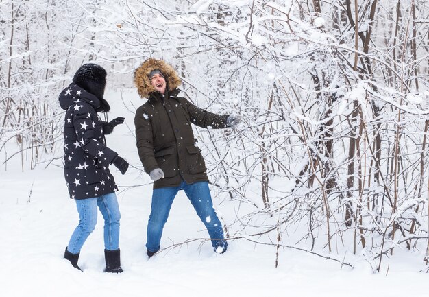 Joven pareja de enamorados se divierten en el bosque nevado. Vacaciones de invierno activas.