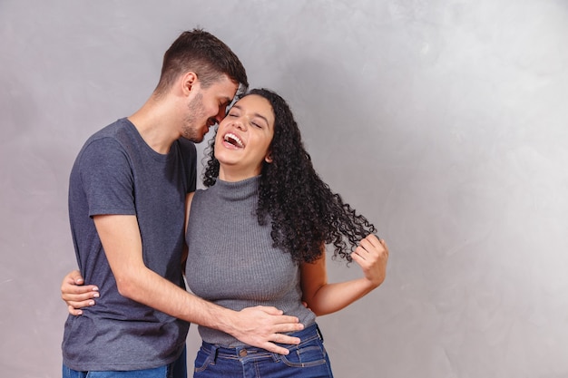 Joven pareja de enamorados enamorados en la pared gris.