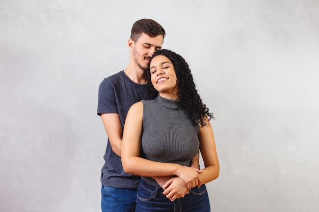 Joven pareja de enamorados enamorados en la pared gris.