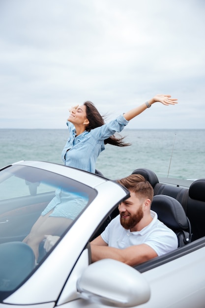 Joven pareja de enamorados en viaje por carretera conduciendo en coche convertible