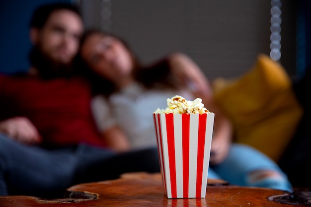 Una joven pareja de enamorados viendo la televisión por la noche cita romántica noche acostada en el sofá comiendo palomitas de maíz