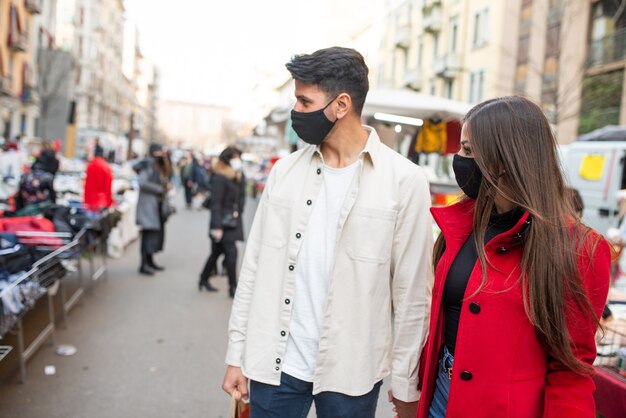 Joven pareja enmascarada de compras en un mercado callejero, concepto de coronavirus covid