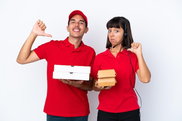 Joven pareja de entrega sosteniendo pizzas y hamburguesas aisladas sobre fondo blanco orgulloso y satisfecho de sí mismo en el concepto de amarte a ti mismo