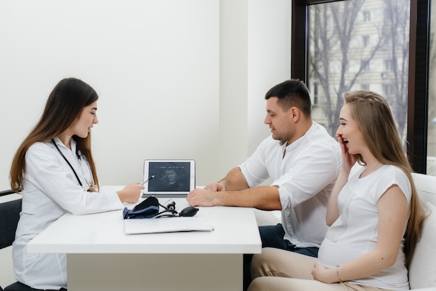 Una joven pareja esperando un bebé para consultar a un ginecólogo después de una ecografía.